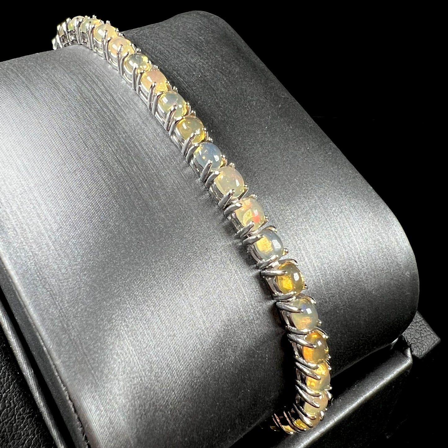A ladies' sterling silver tennis style bracelet set with natural orange yellow Mexican fire opals.