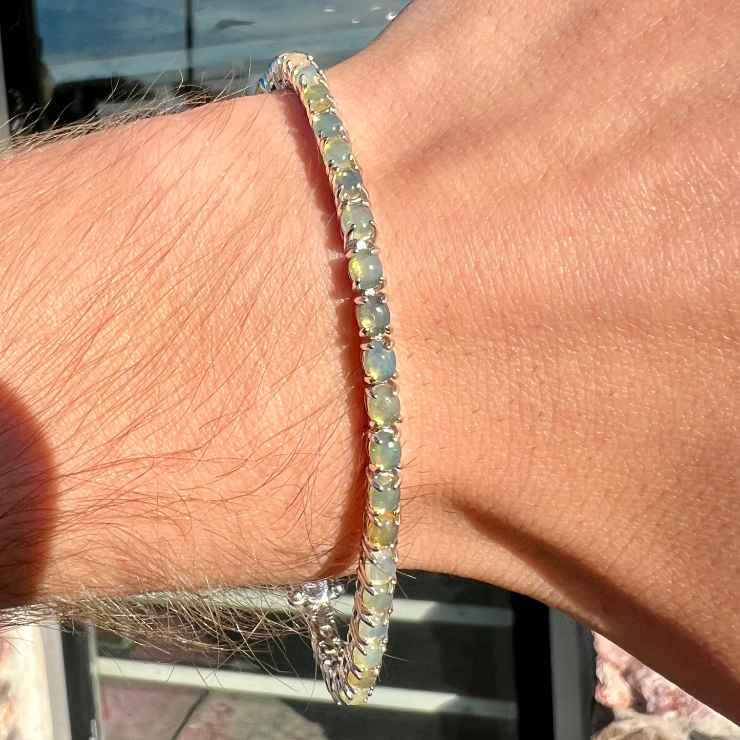 A ladies' sterling silver tennis style bracelet set with natural orange yellow Mexican fire opals.