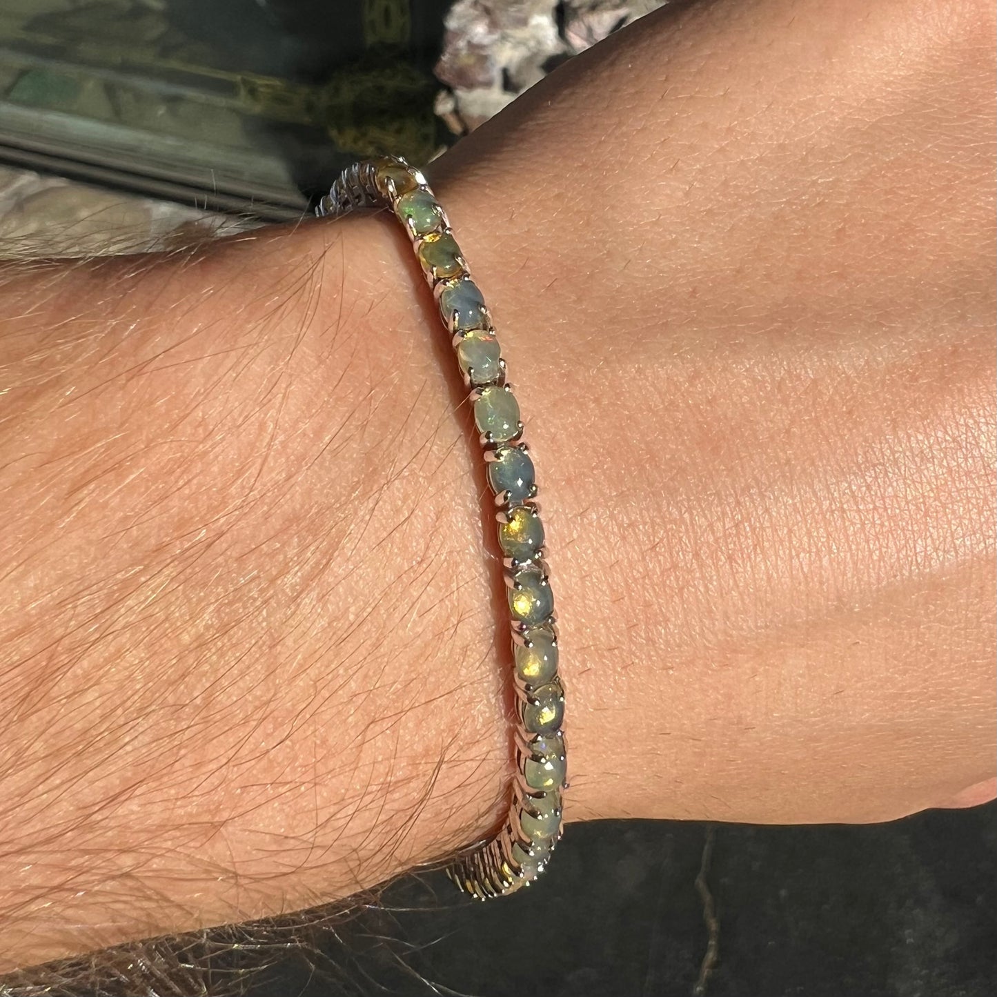 A ladies' sterling silver tennis style bracelet set with natural orange yellow Mexican fire opals.