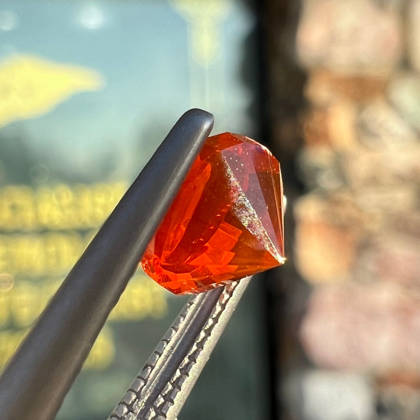 A faceted round cut natural Mexican fire opal stone. The stone is bright orange in color.