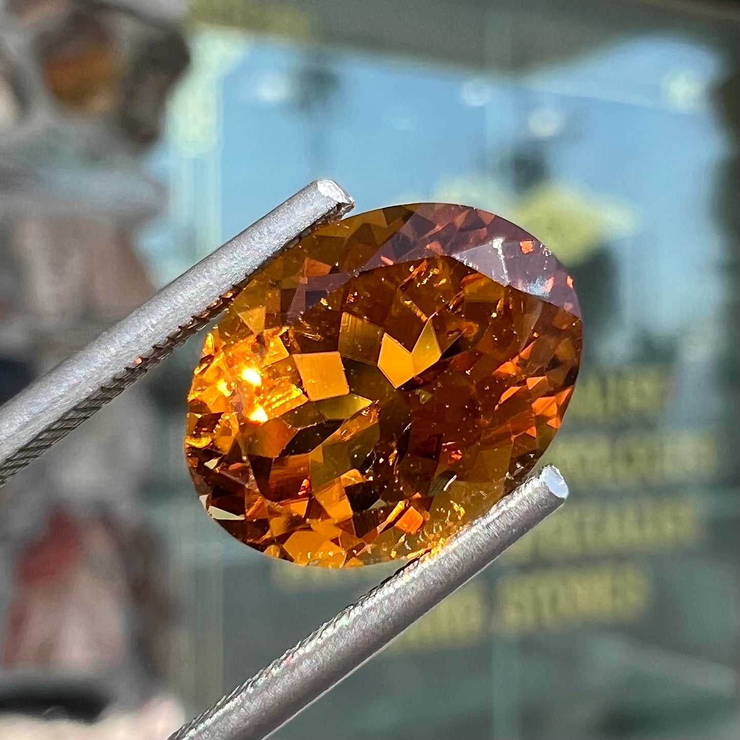 A loose, faceted oval cut orange dravite tourmaline gemstone.