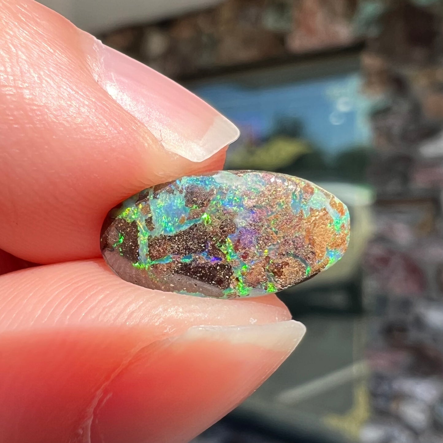 A loose, oval cabochon cut Koroit boulder opal stone. The opal has a bright green color.