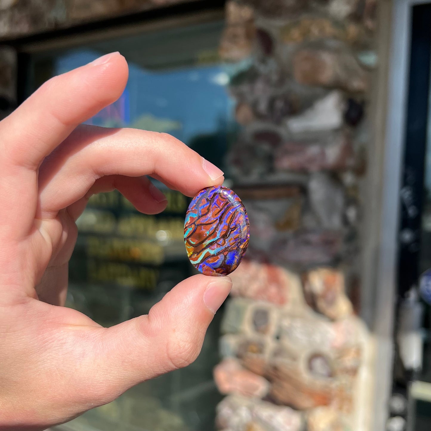 A loose, oval cabochon cut boulder opal from Koroit, Australia. The opal has violet and purple veins.