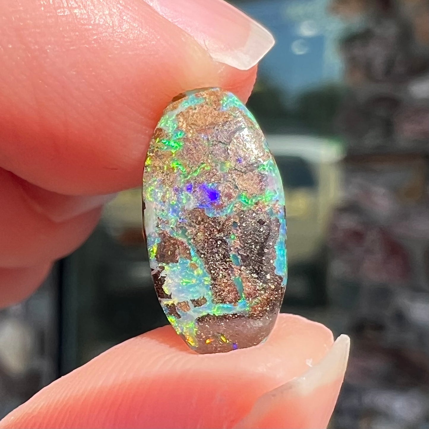 A loose, oval cabochon cut Koroit boulder opal stone. The opal has a bright green color.