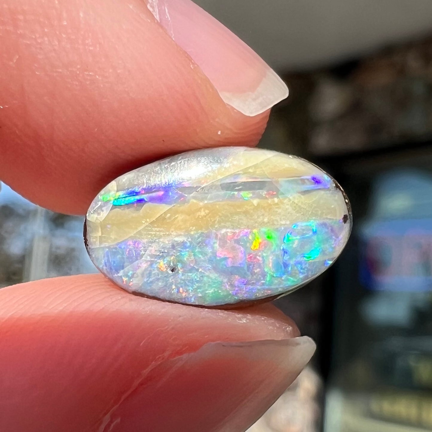 An oval cabochon cut boulder opal from Quilpie, Australia. The opal has multicolor color play.