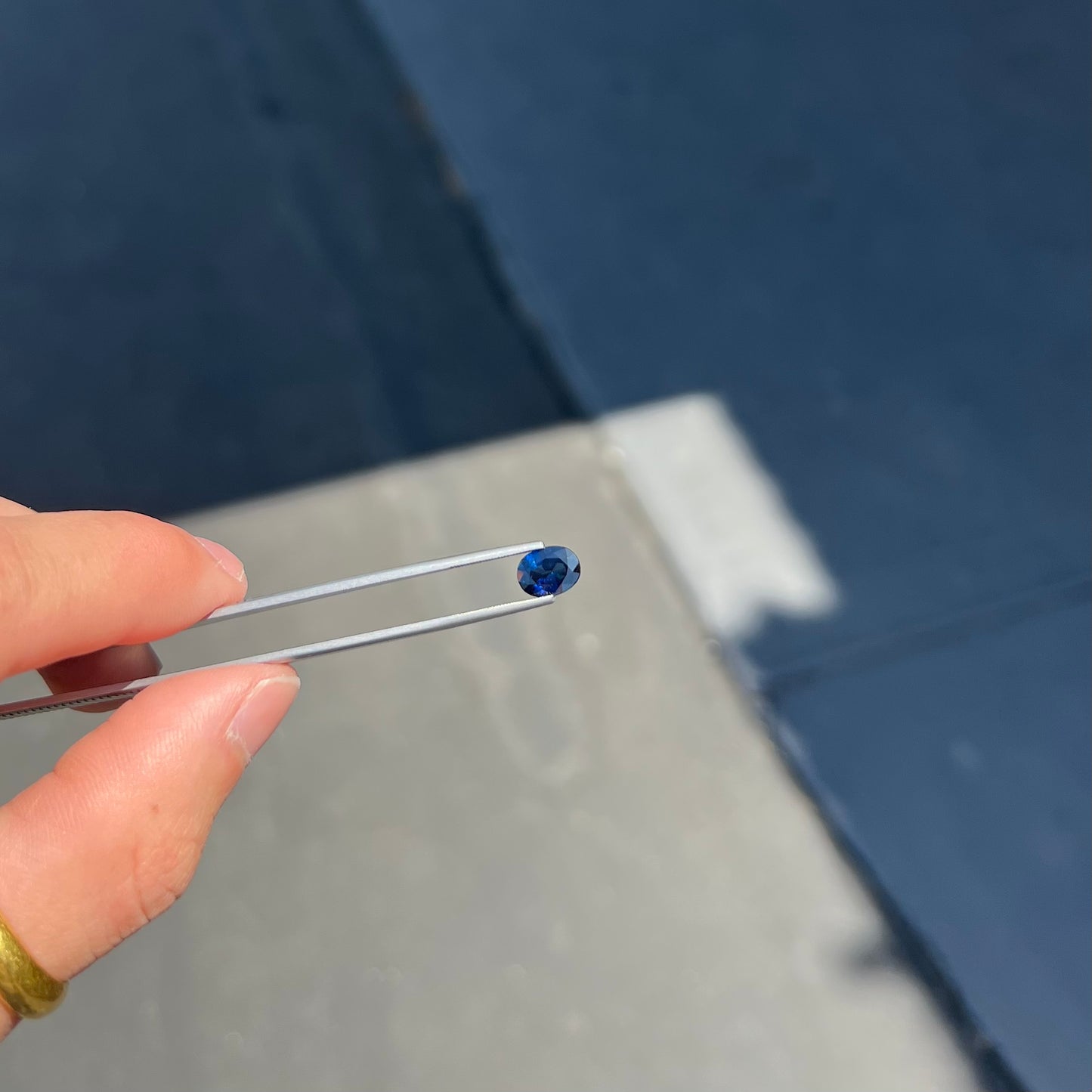 A loose, faceted oval cut natural blue sapphire gemstone.