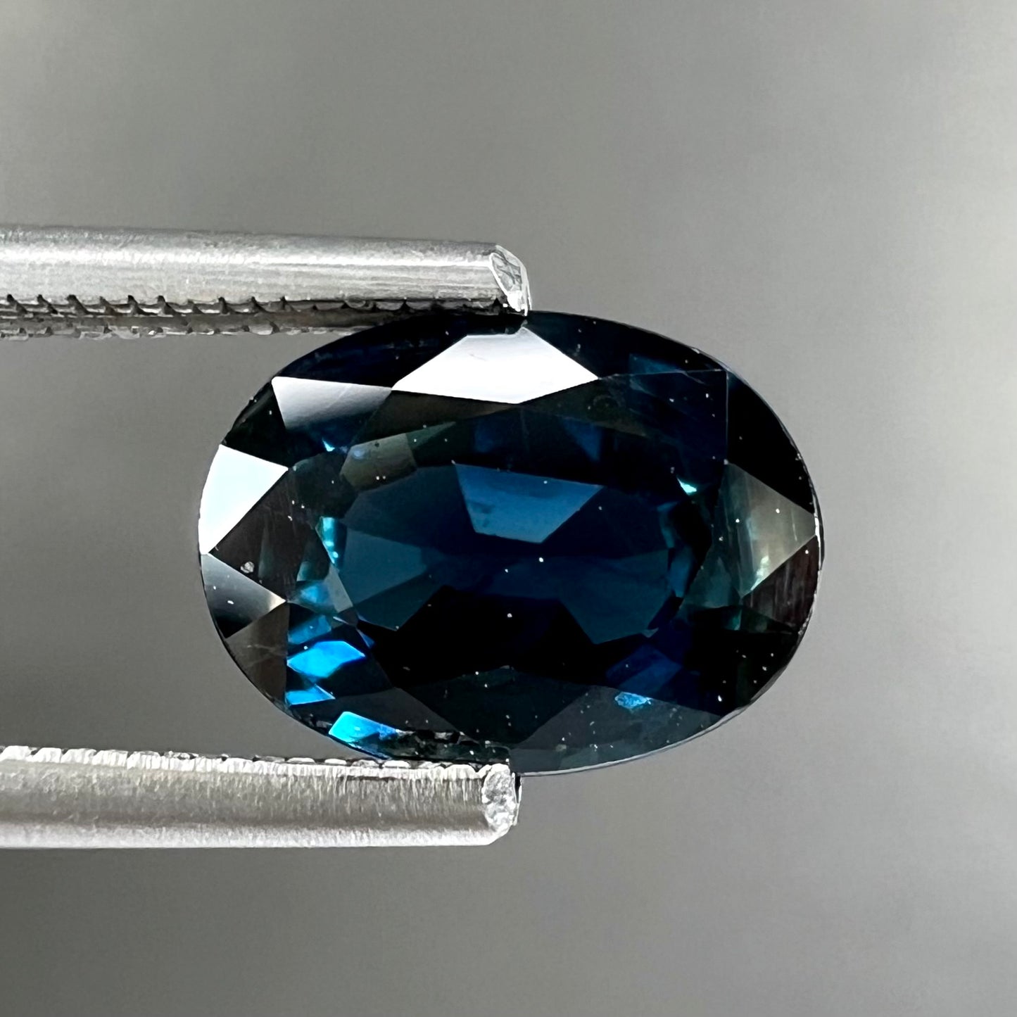 A loose, faceted oval cut natural blue sapphire gemstone.