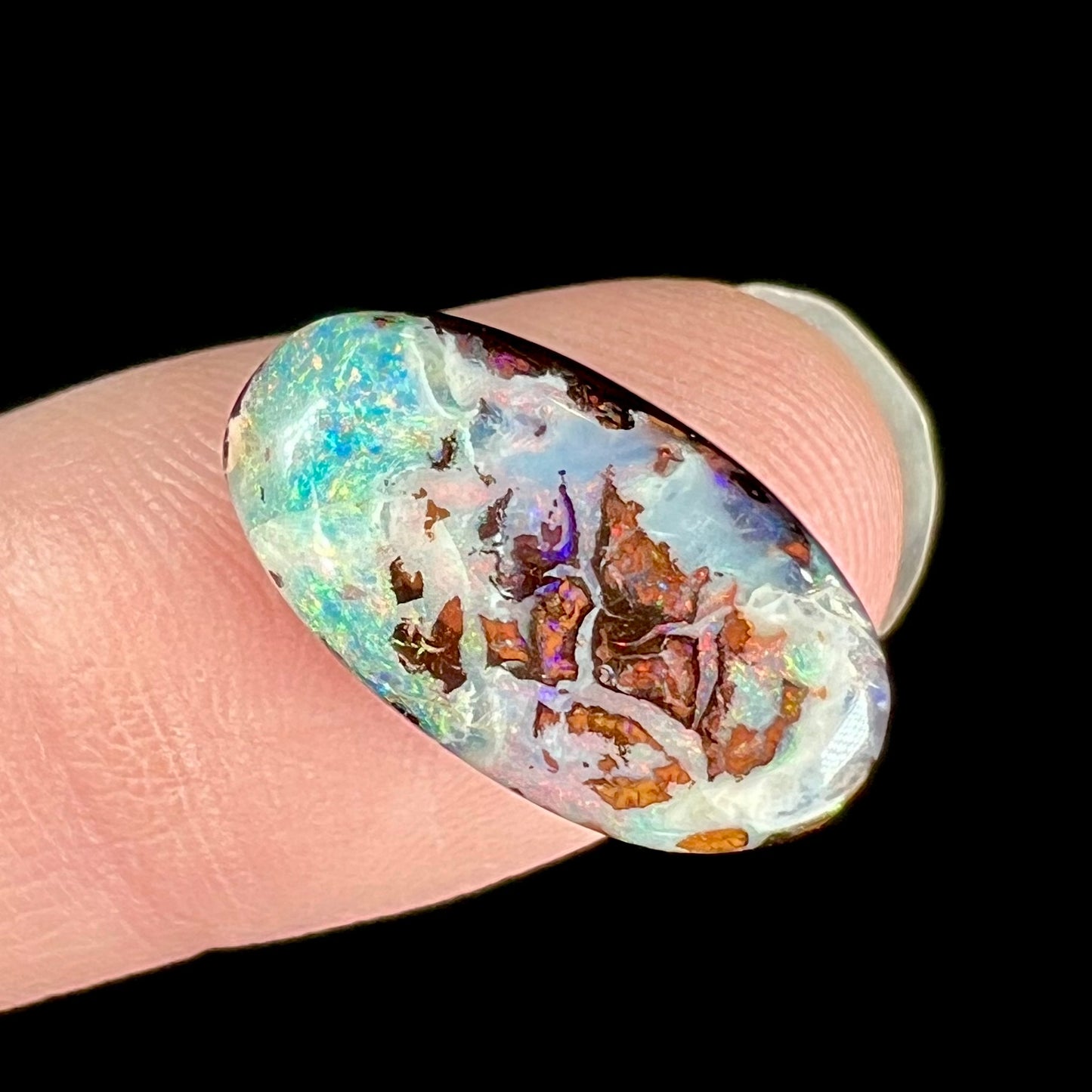 An oval cabochon cut boulder opal stone from Koroit, Australia. The opal has a white body tone.