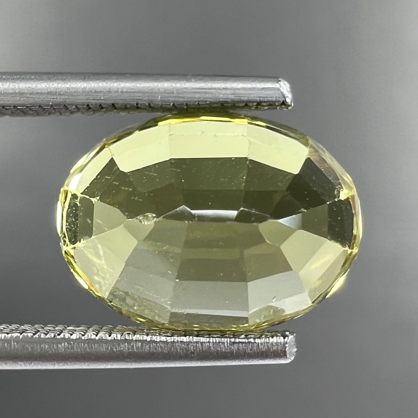 A loose, oval cut greenish yellow chrysoberyl stone.