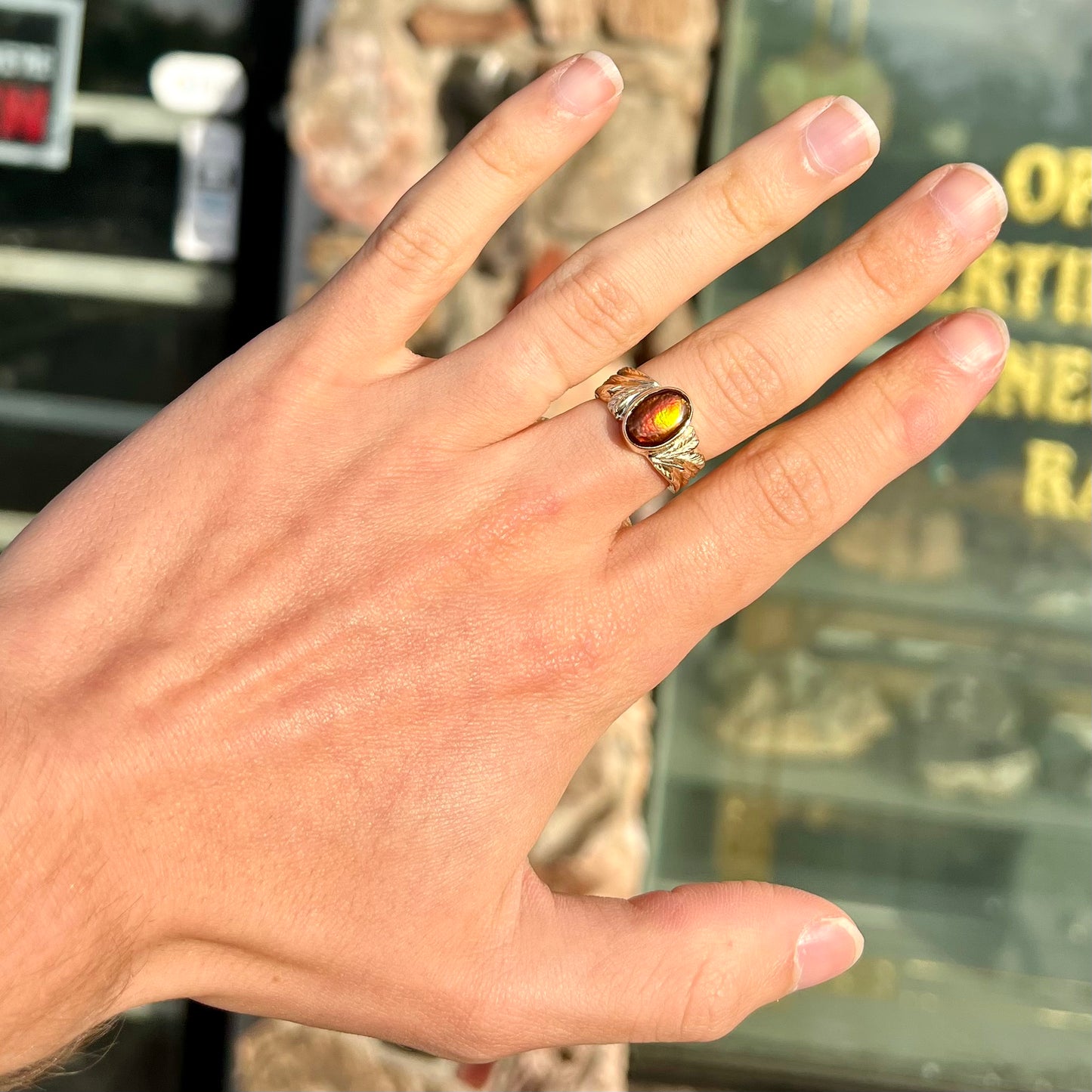A unisex oval cabochon cut fire agate ring cast in yellow gold. The stone flashes green and red colors.