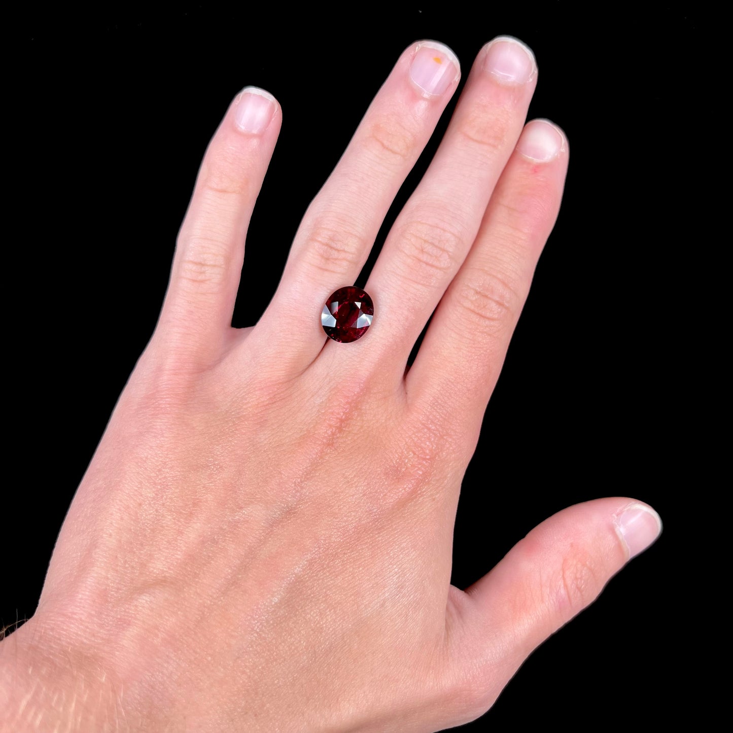 A loose, oval cut purplish red rubellite tourmaline stone.