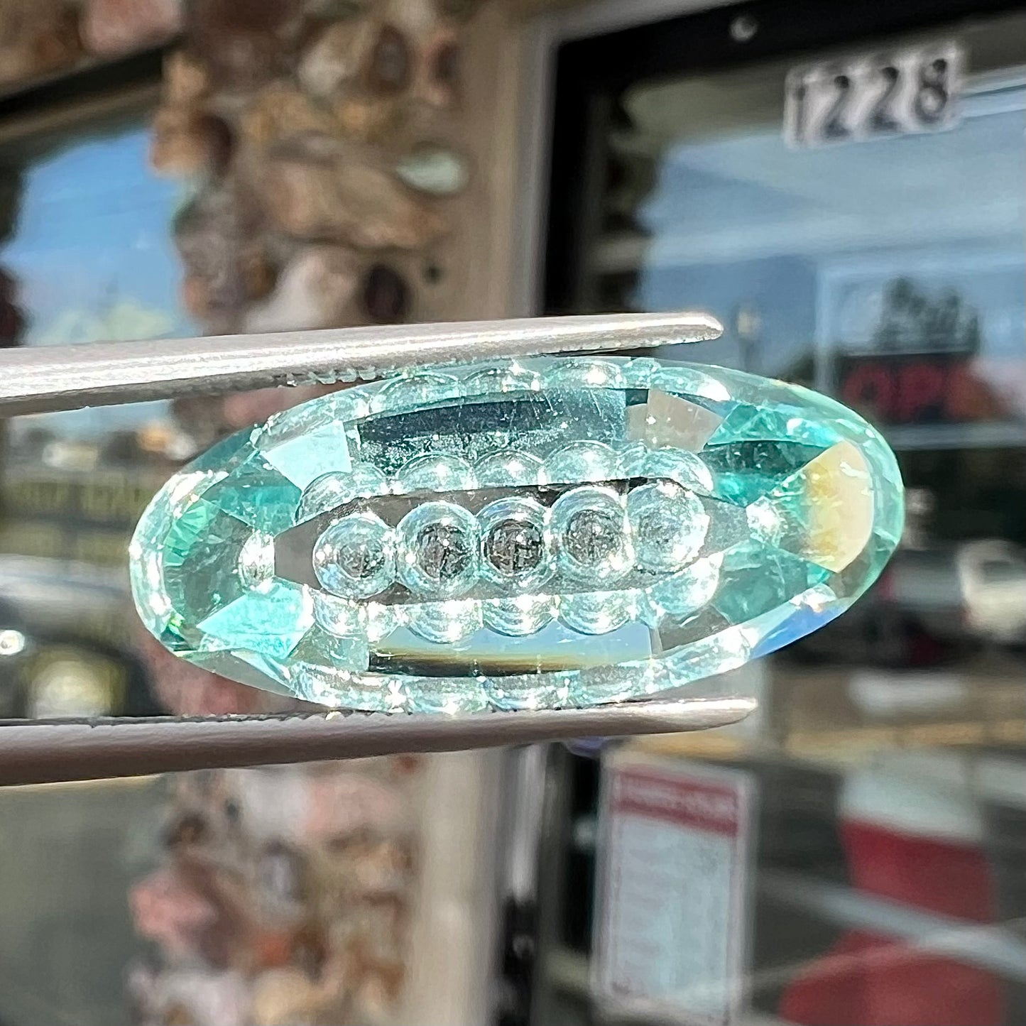 An oval fantasy cut greenish blue aquamarine stone cut by gem carver, Arthur Lee Anderson.