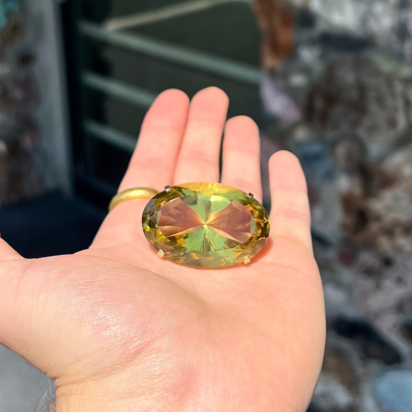 A faceted oval cut lemon quartz gemstone pendant in gold plated sterling silver. The quartz is a green-yellow color.