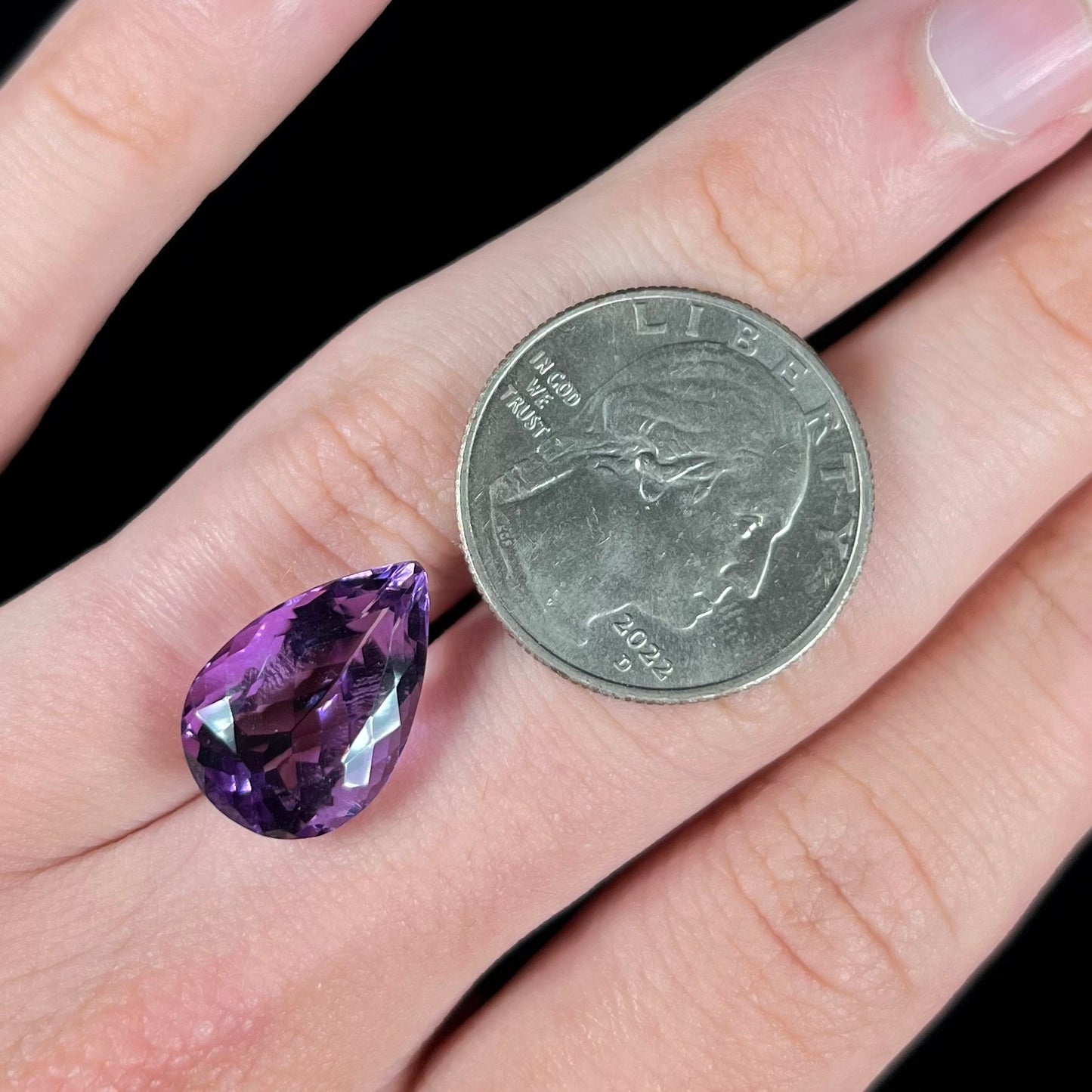 A loose, pear shaped amethyst gemstone. The stone is a medium purple color.
