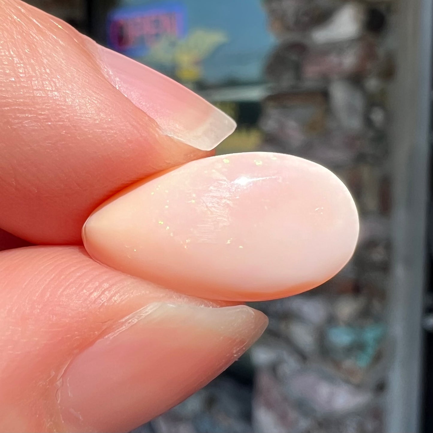 A loose, pear shaped pink Peruvian opal cabochon.  The opal has green play of color.