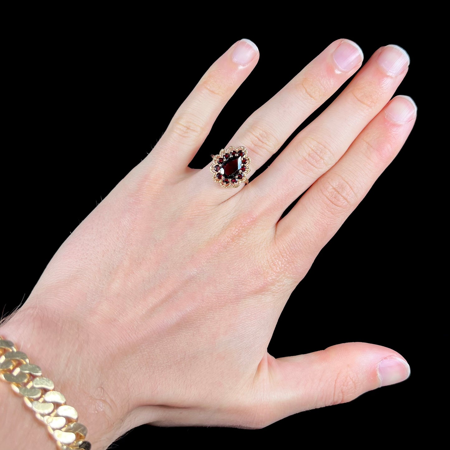 A vintage, 1940's style yellow gold ring set with a pear shaped almandine garnet. A halo of round garnets surround the center stone.