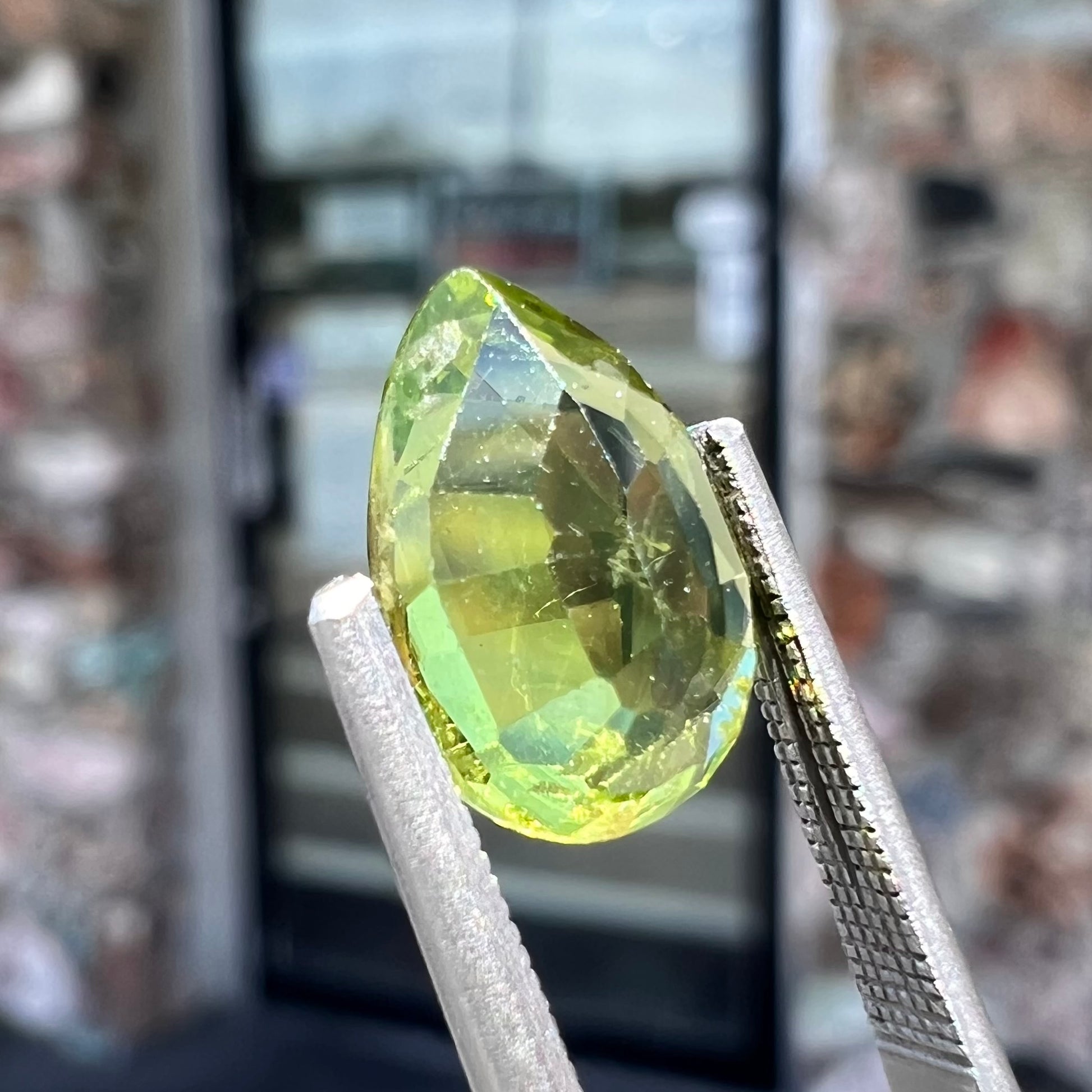 A loose, yellow green, pear shaped peridot gemstone.