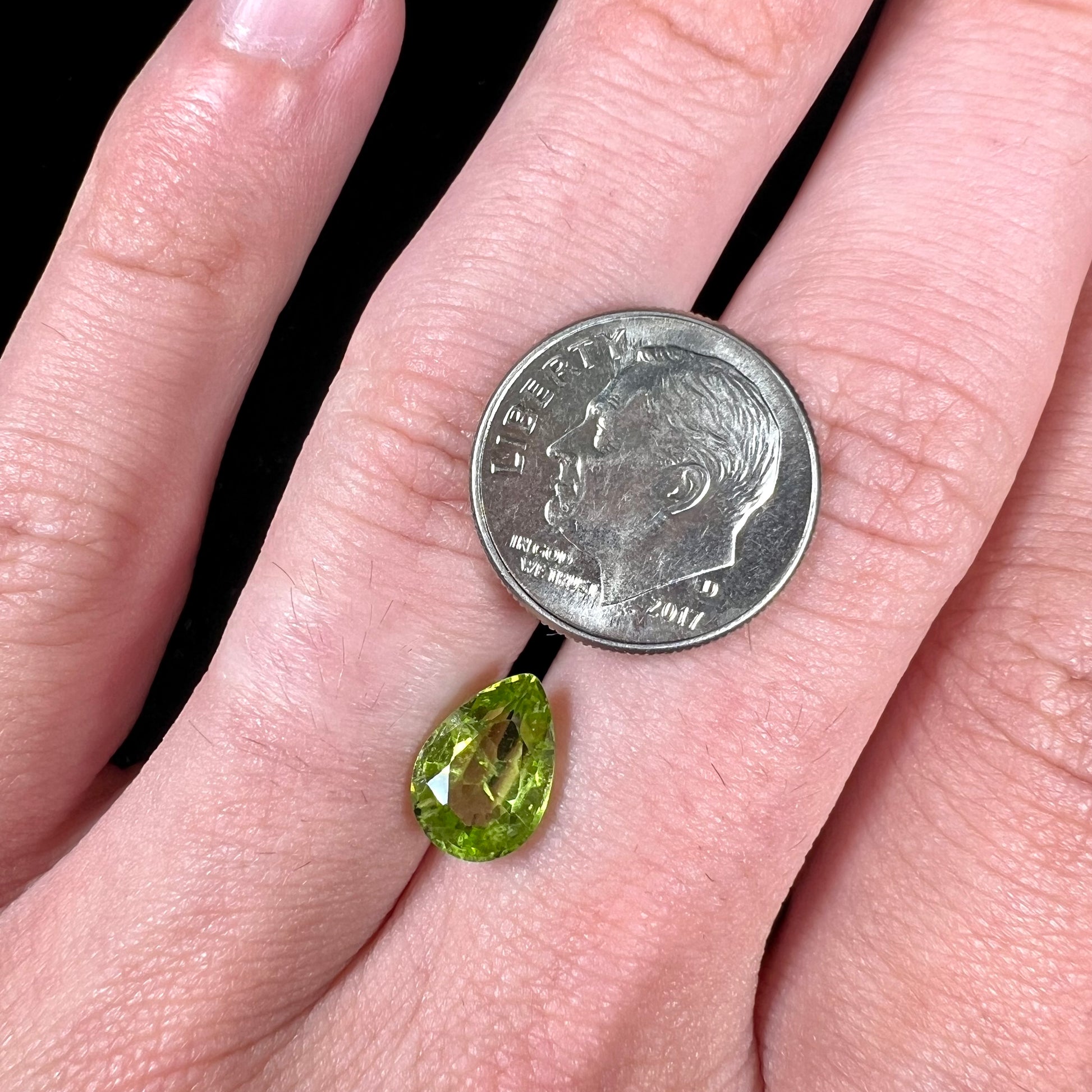 A loose, yellow green, pear shaped peridot gemstone.