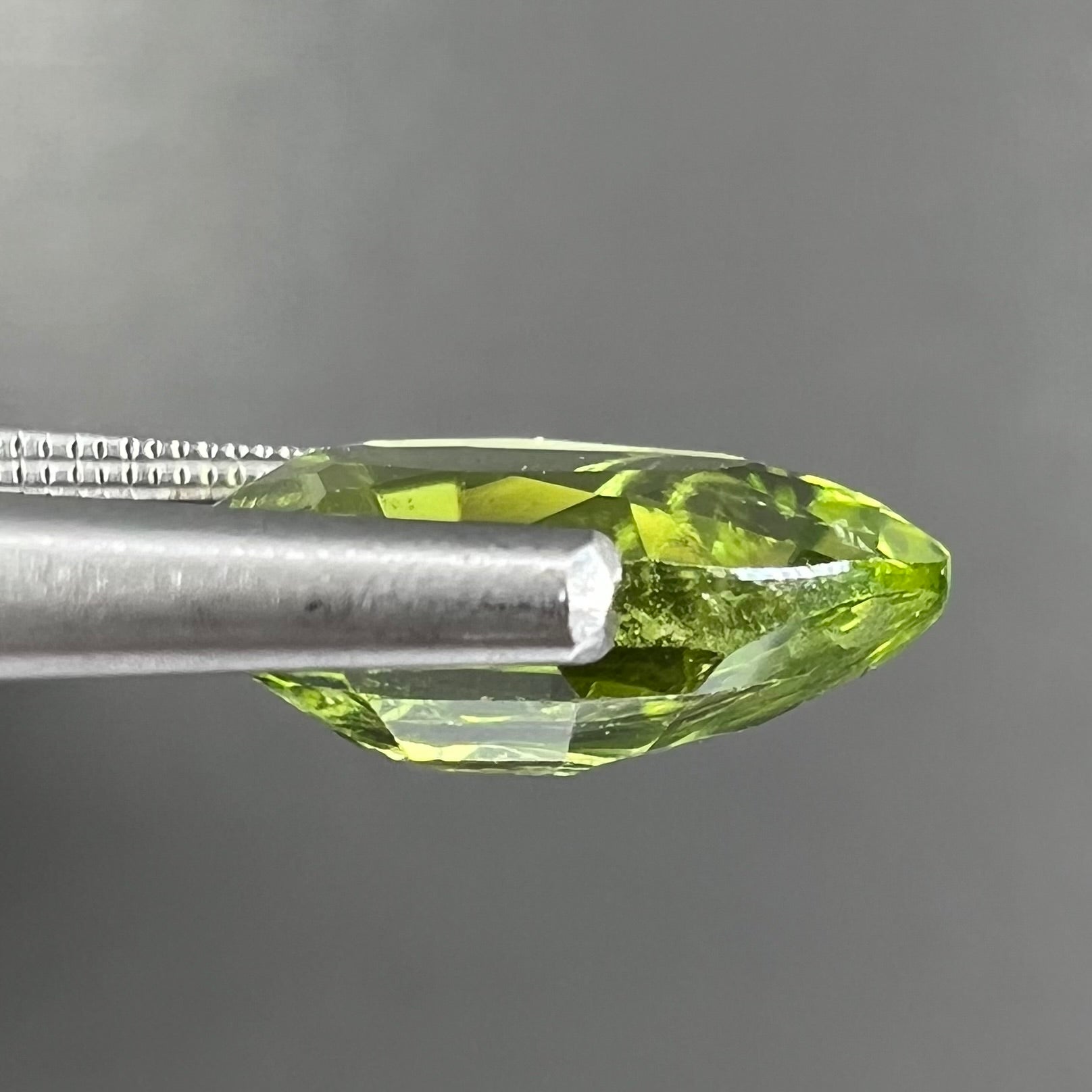 A loose, yellow green, pear shaped peridot gemstone.
