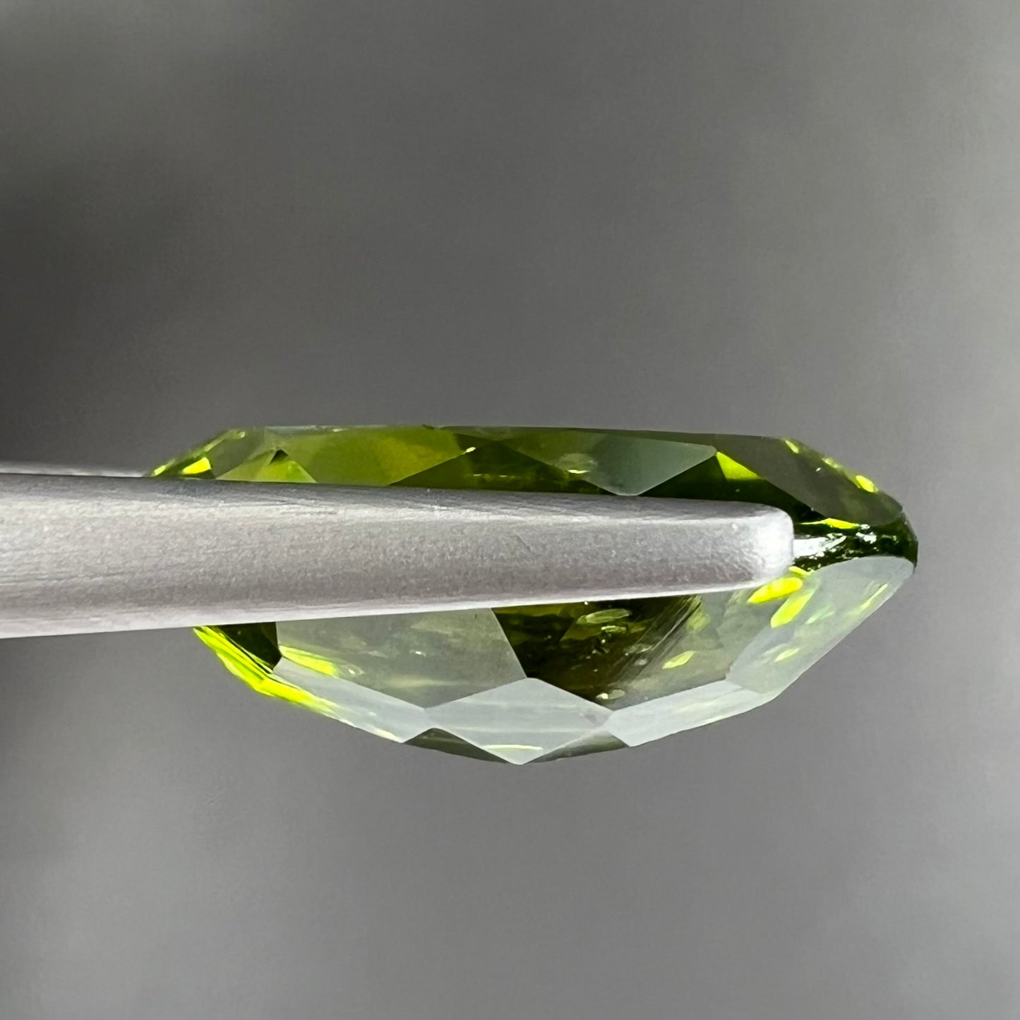 A loose, marquise cut peridot gemstone. The stone is an olive green color.