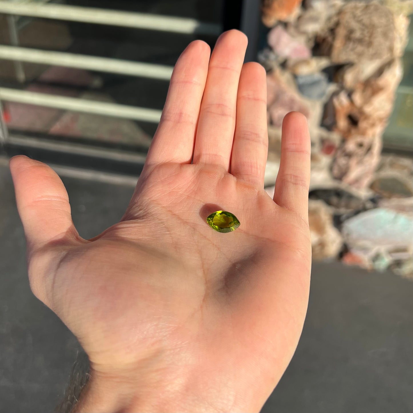 A loose, marquise cut peridot gemstone. The stone is an olive green color.