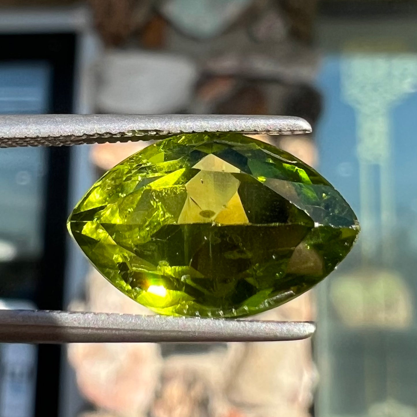 A loose, marquise cut peridot gemstone. The stone is an olive green color.