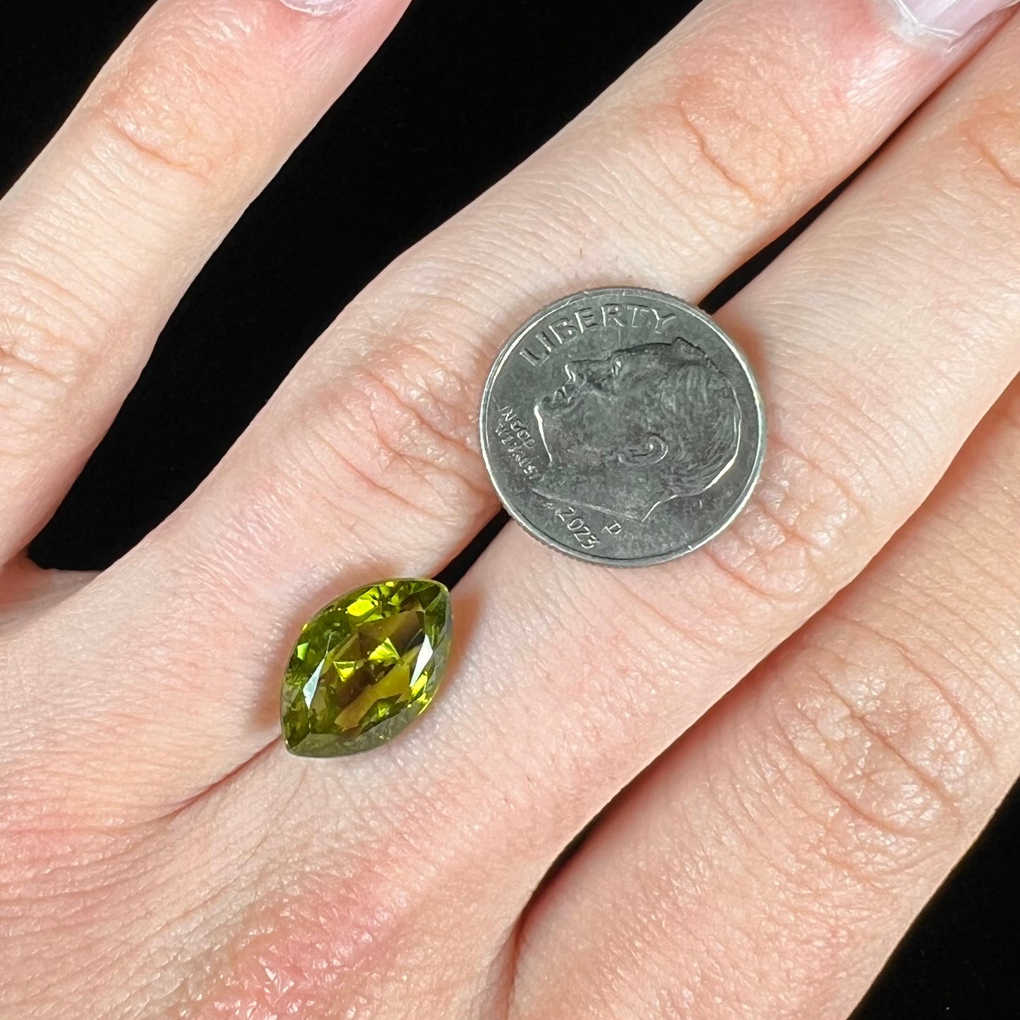 A loose, marquise cut peridot gemstone. The stone is an olive green color.