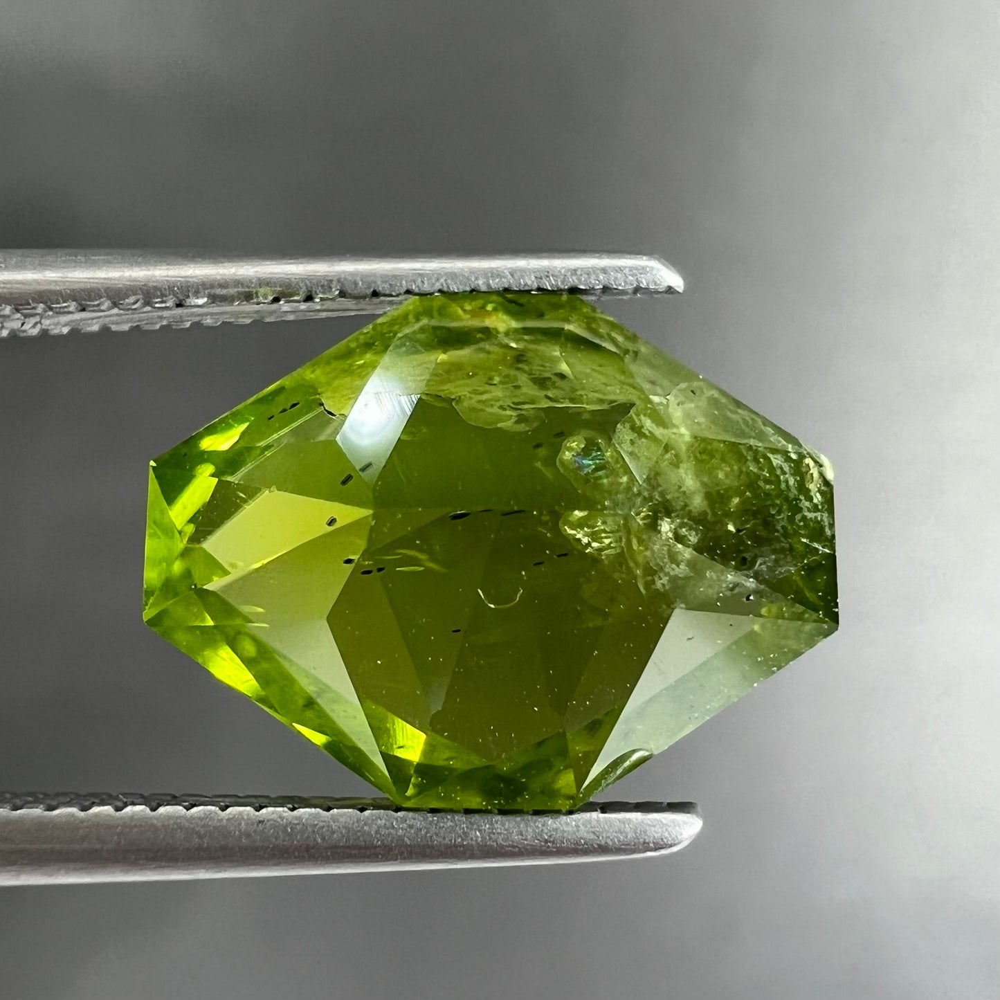 A loose, modified octagon peridot stone. The stone is a yellow green color.