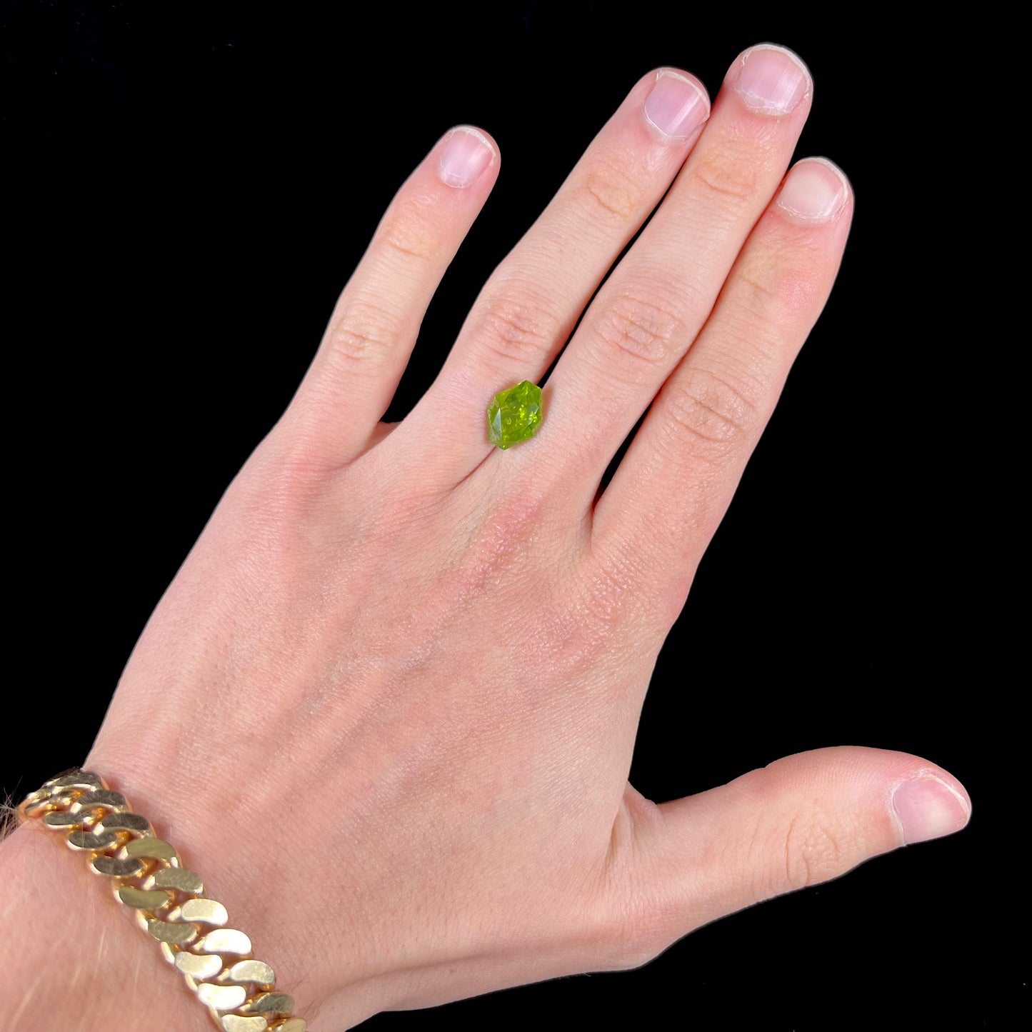 A loose, modified octagon peridot stone. The stone is a yellow green color.