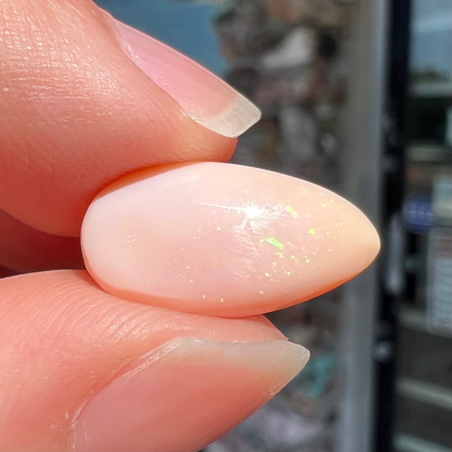 A loose, pear shaped pink Peruvian opal cabochon.  The opal has green play of color.