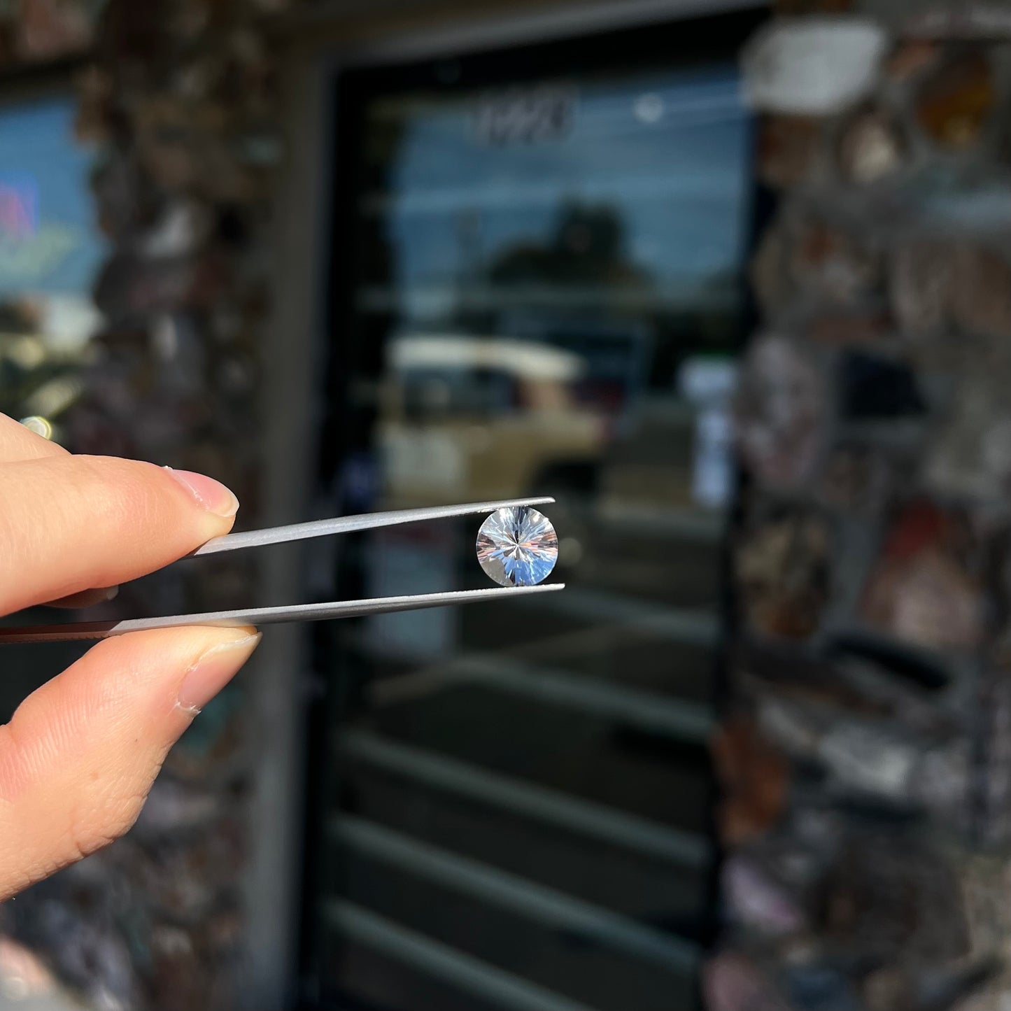A round brilliant cut petalite gemstone. The stone is colorless.