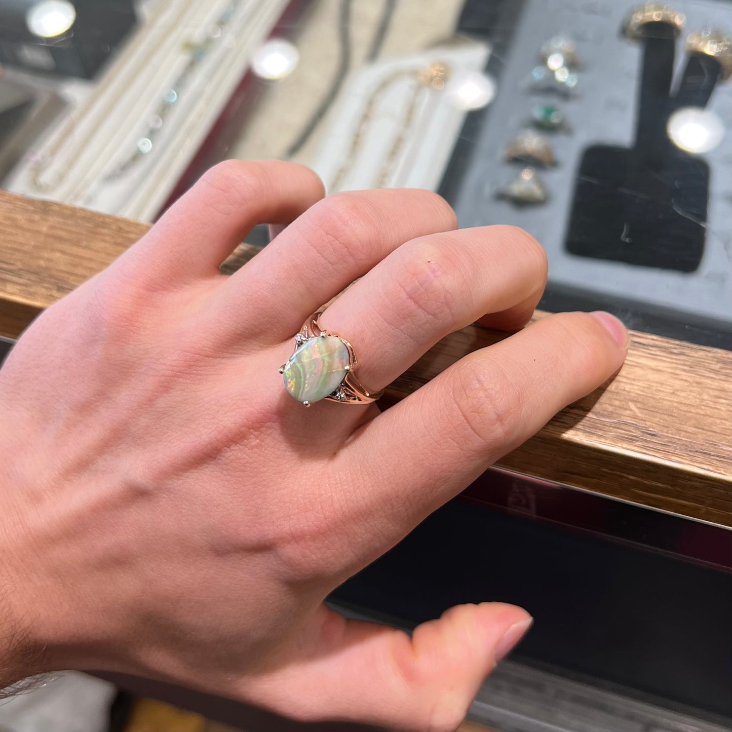 A ladies' Australian boulder opal ring set in yellow gold with diamond accents. The opal shimmers green and pink and has fissure inclusions.