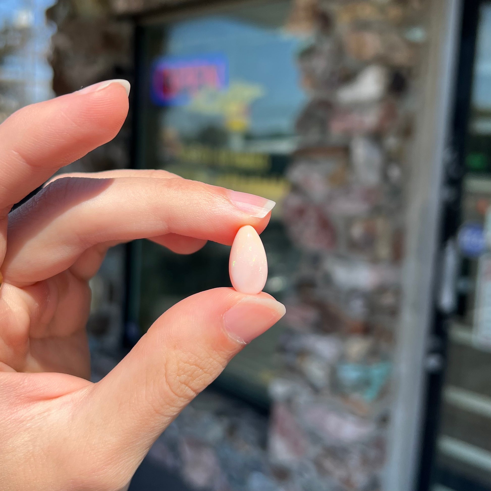 A loose, pear shaped pink Peruvian opal cabochon.  The opal has green play of color.