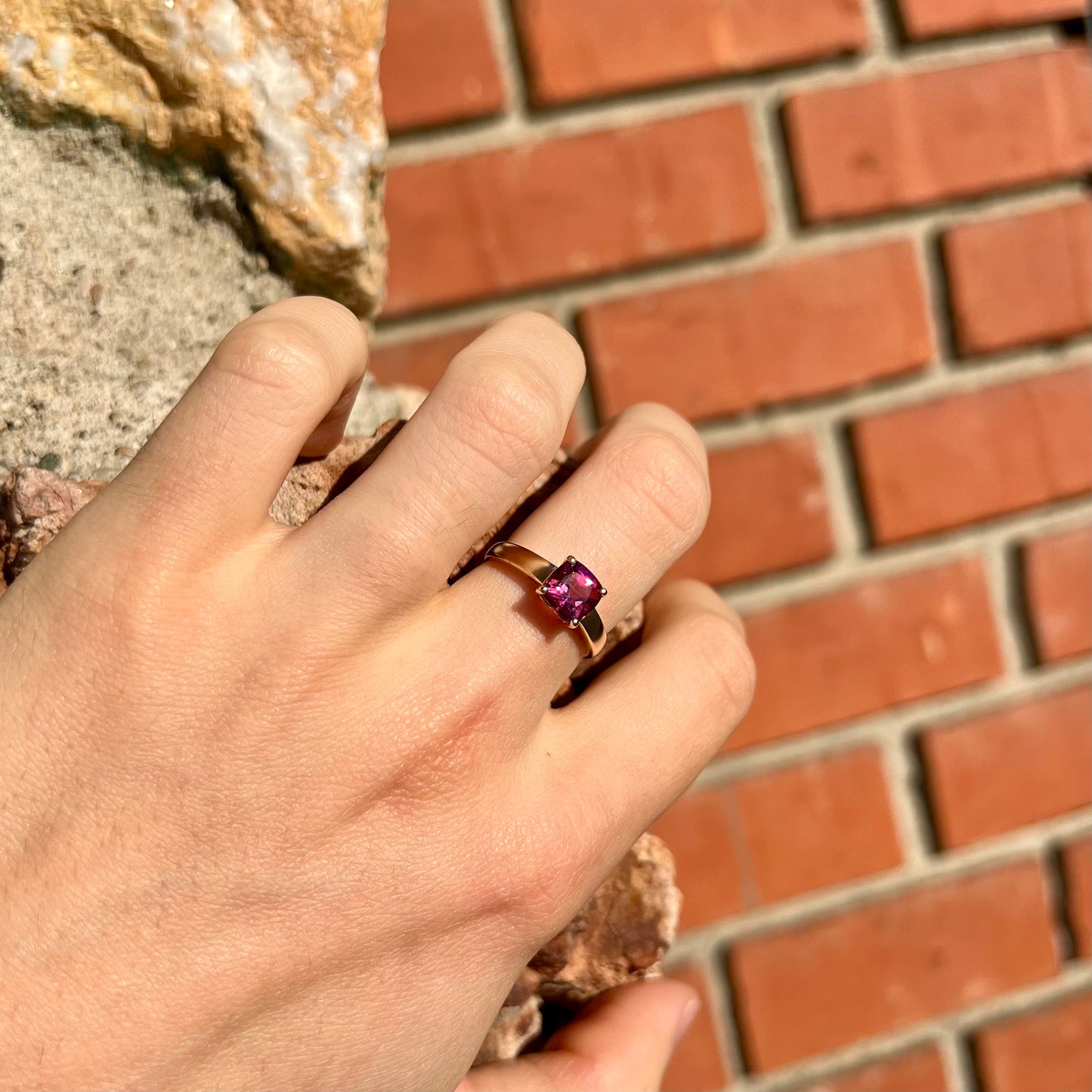 A ladies' cushion cut pink tourmaline solitaire ring in yellow gold.