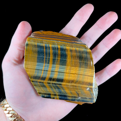 A polished slab of yellow tiger's eye with blue streaks.