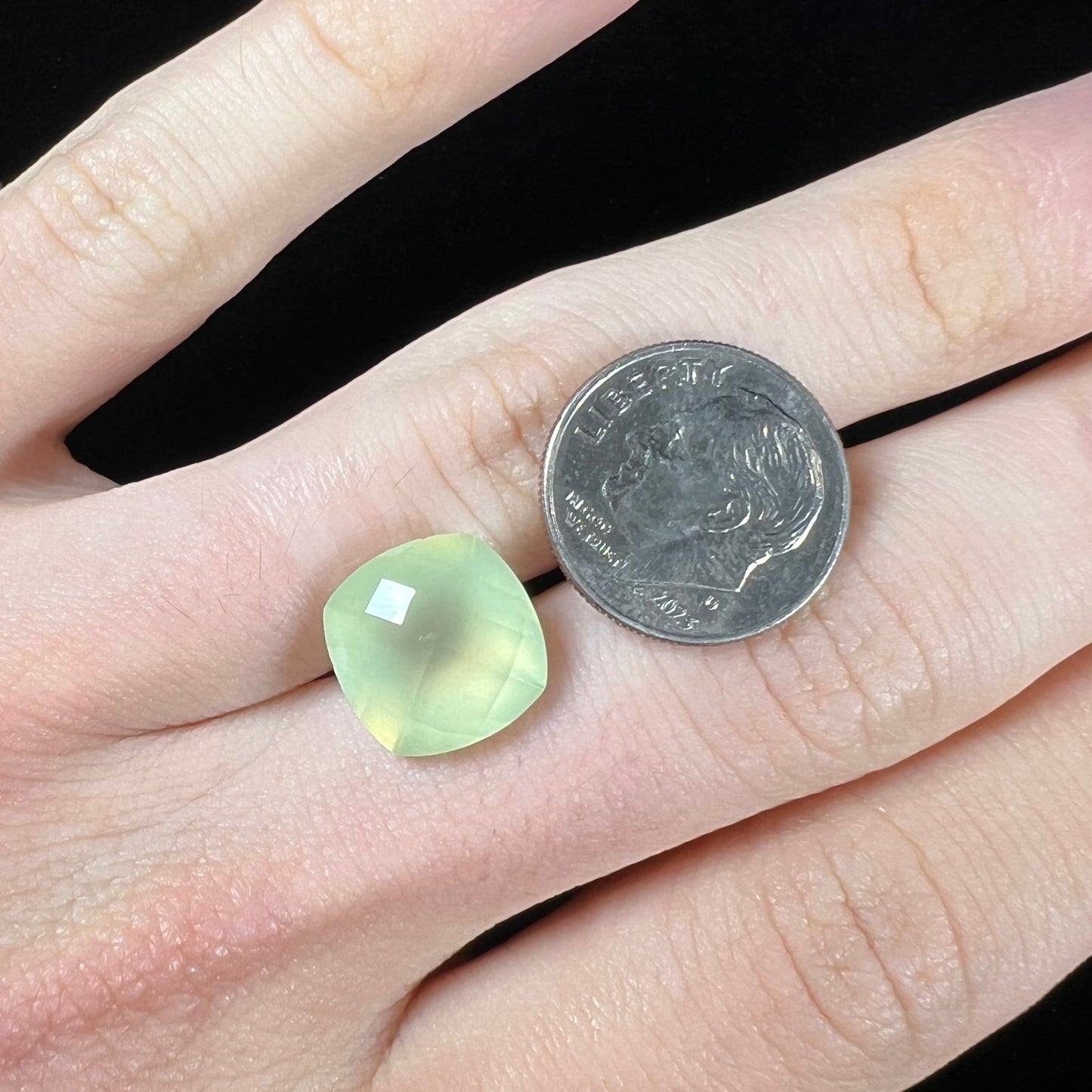 A loose, checkerboard cushion cut prehnite gemstone. The stone is a sleepy yellow green color.