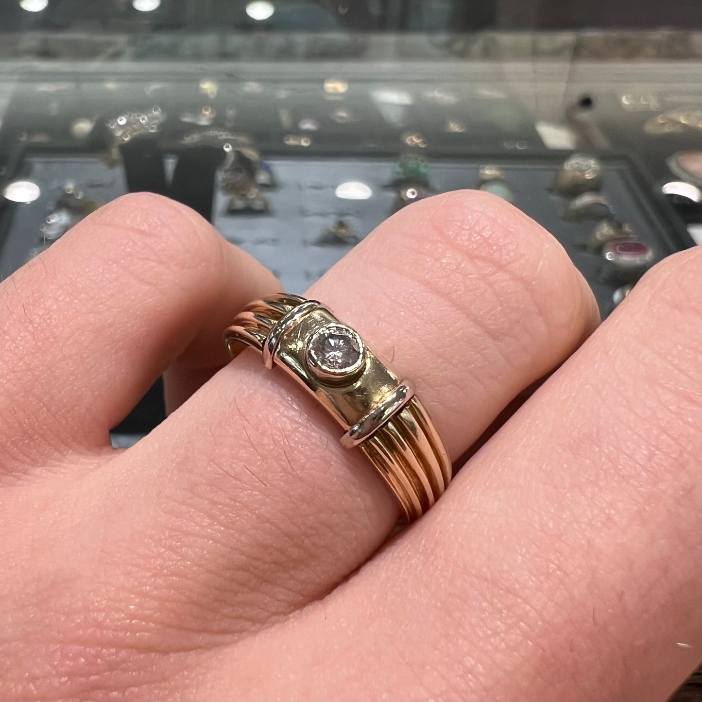 A unisex, vintage style two tone yellow and white gold wedding ring bezel set with a round diamond.