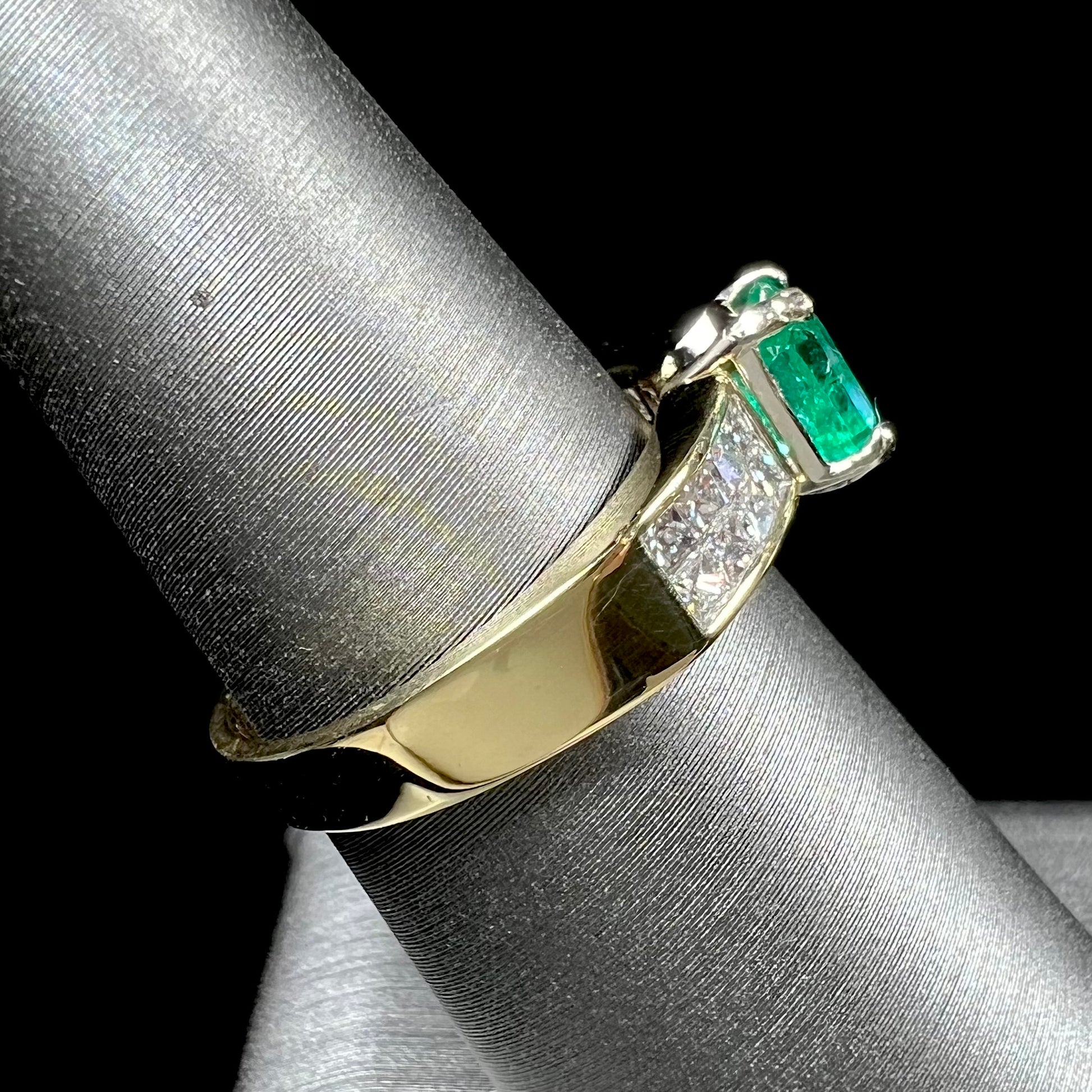 An 18 karat yellow gold ladies' emerald ring, channel set with princess cut diamonds.