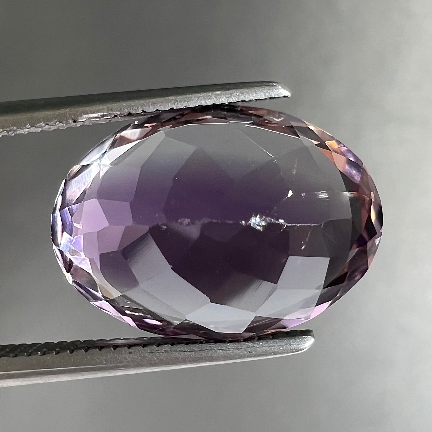 A faceted oval cut amethyst gemstone. The stone is a light purple color.