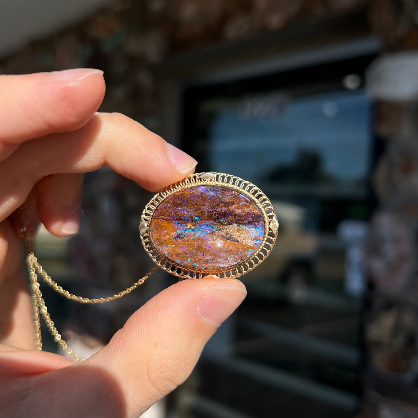 A yellow gold filigree style brooch/pendant combination piece set with a purple opalized wood stone from Duck Creek, Australia.