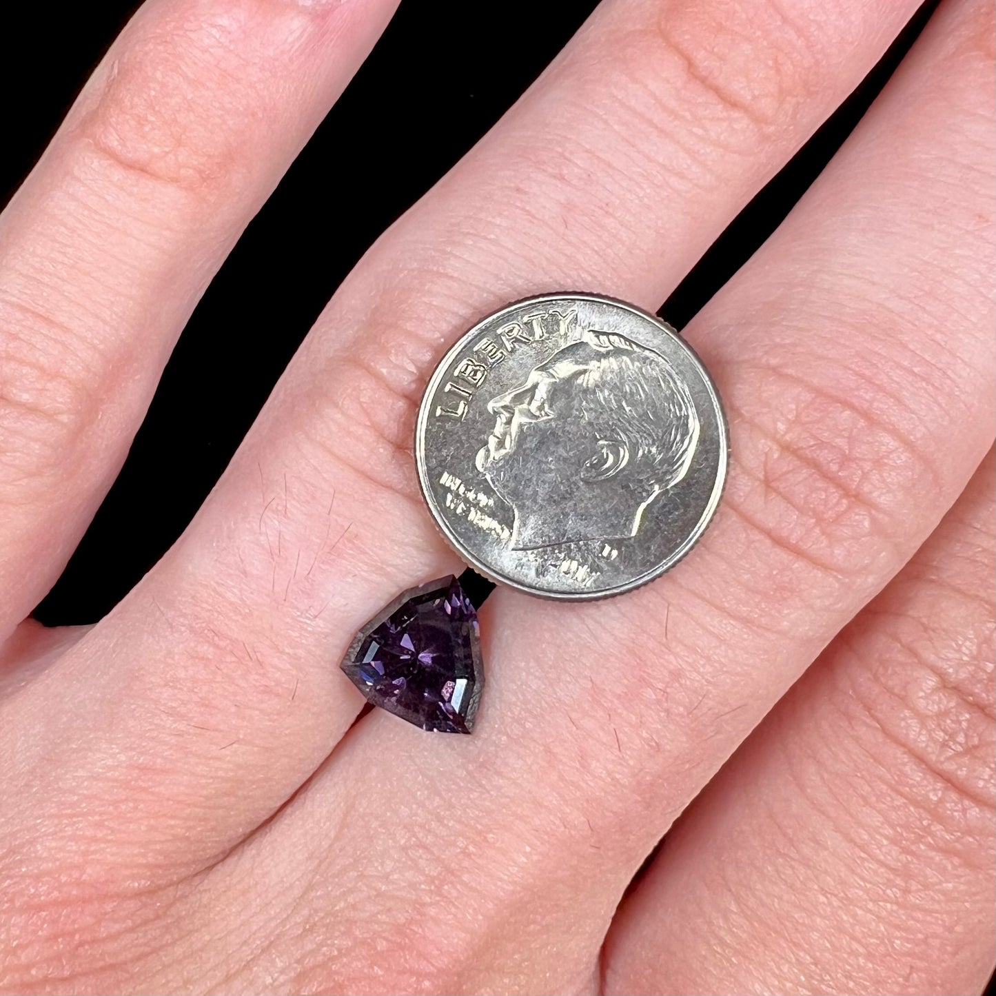A loose, natural purple trillion cut spinel gemstone.