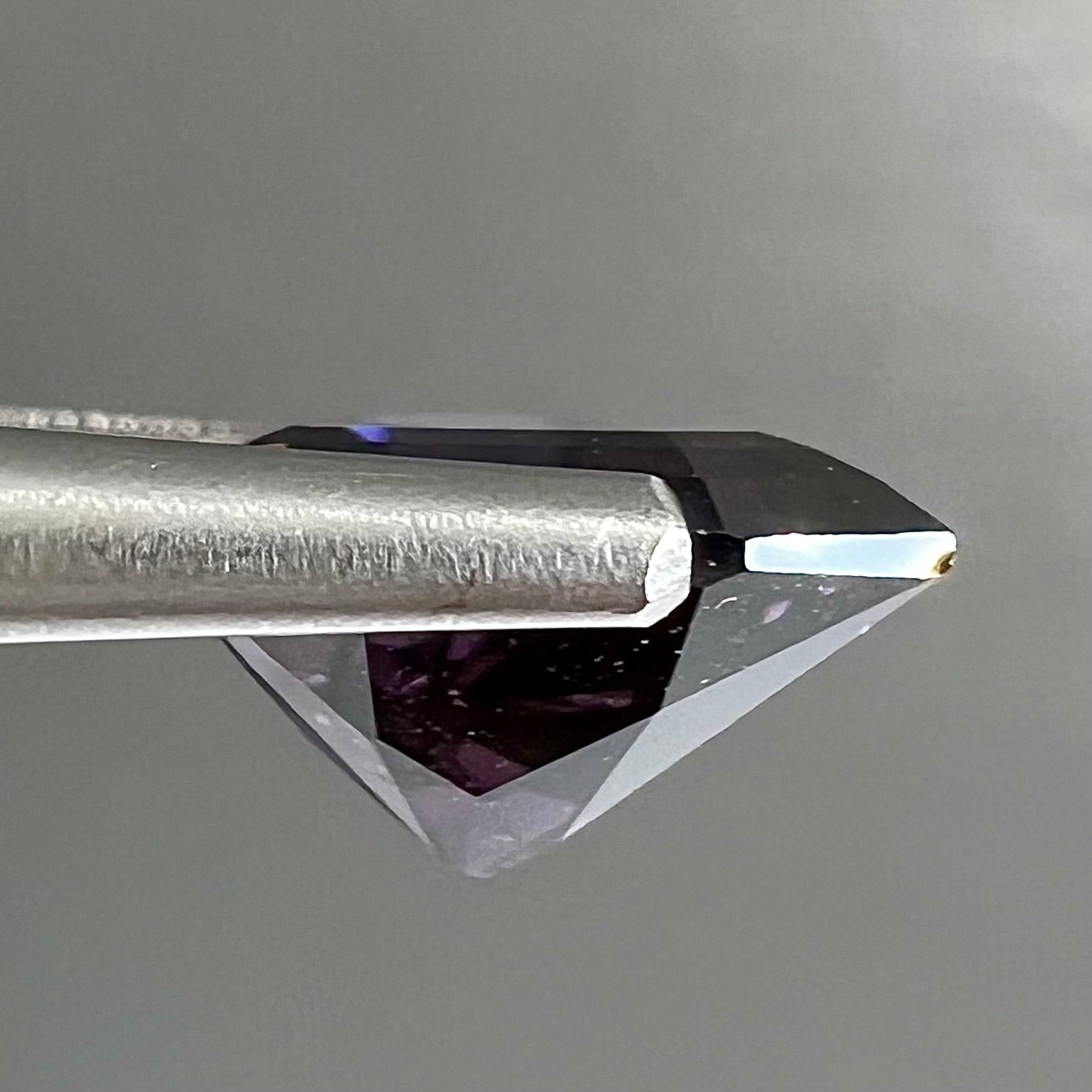A loose, natural purple trillion cut spinel gemstone.