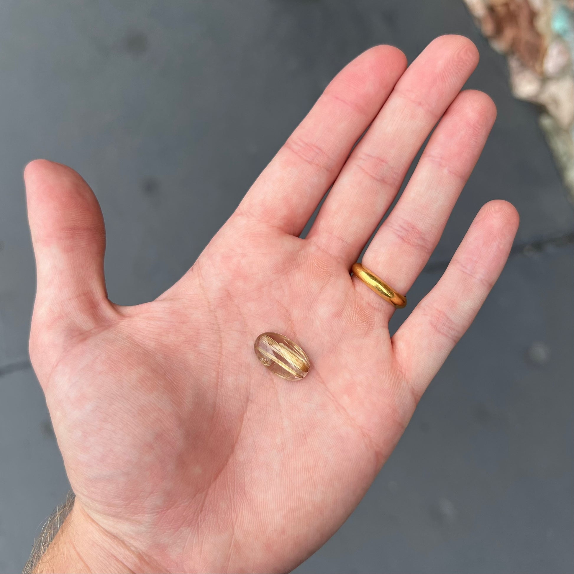 A loose, oval cabochon cut cat's eye golden rutilated quartz stone.