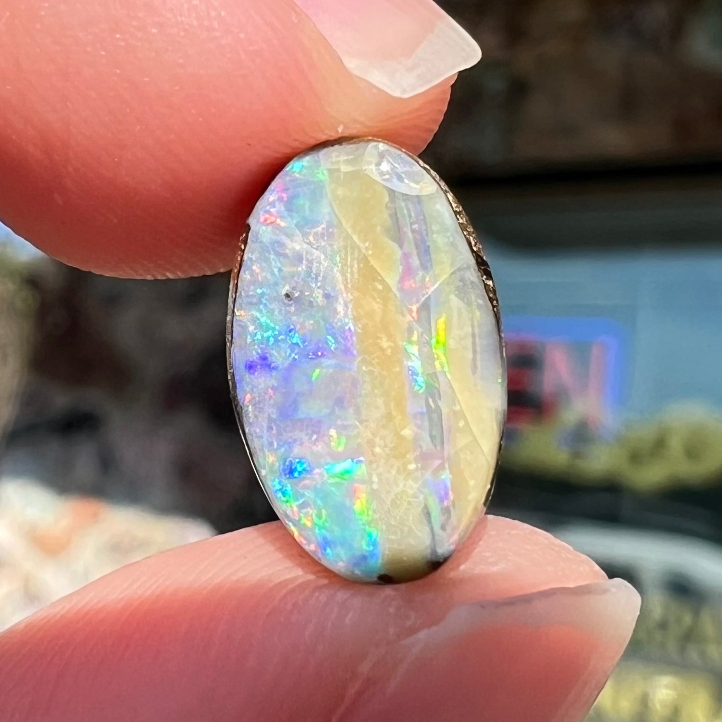 An oval cabochon cut boulder opal from Quilpie, Australia. The opal has multicolor color play.