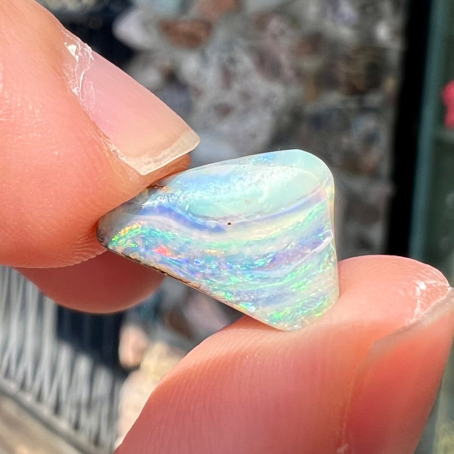 A loose, freeform boulder opal stone from Quilpie, Australia. The opal has a fissure inclusion.