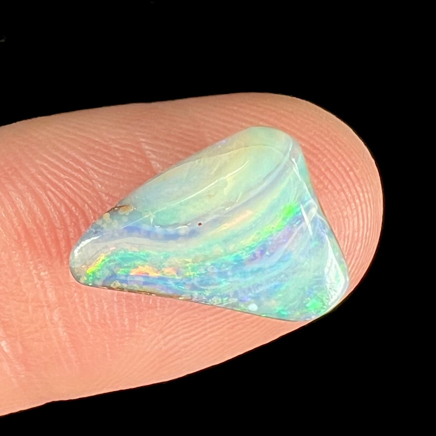A loose, freeform boulder opal stone from Quilpie, Australia. The opal has a fissure inclusion.