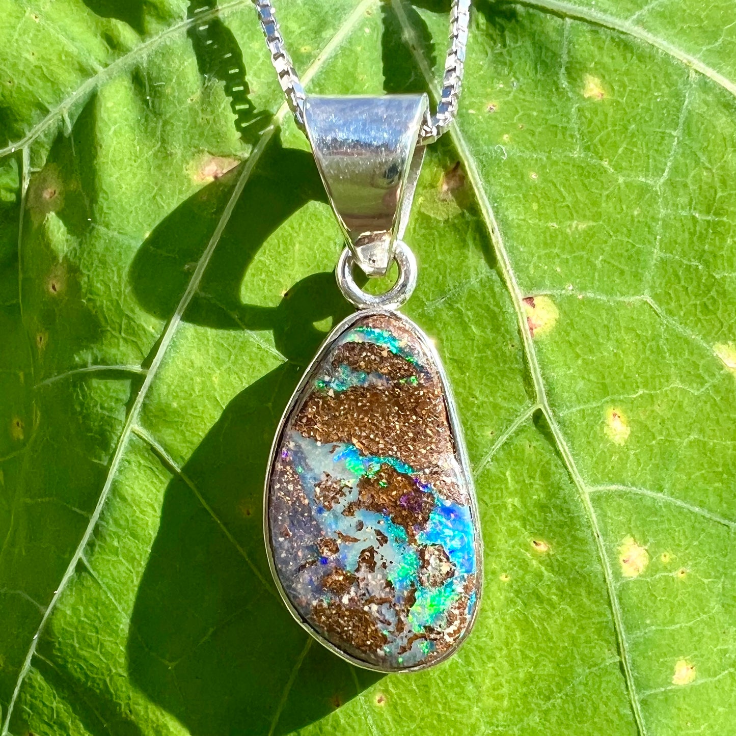 A sterling silver necklace set with a rainbow boulder opal stone.