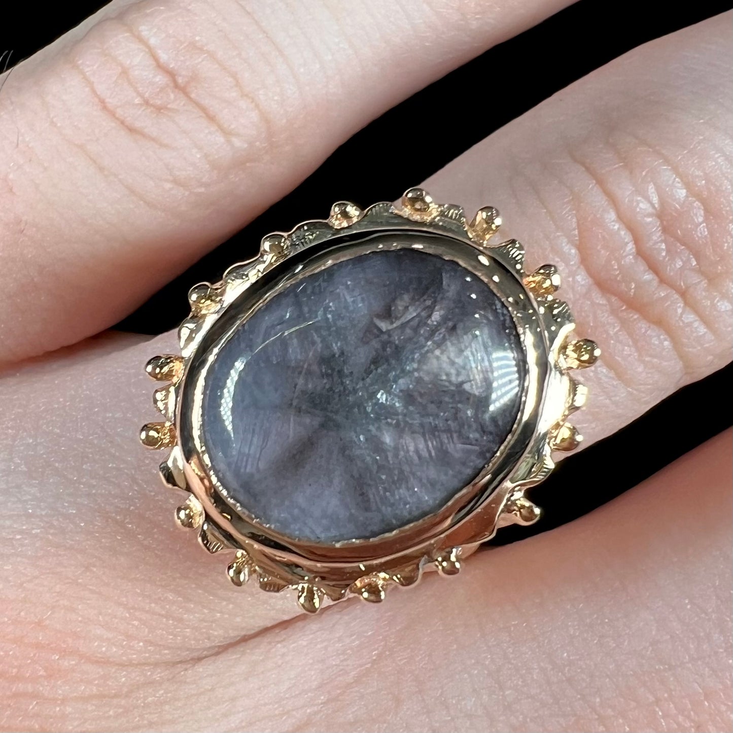 A ladies' yellow gold solitaire ring mounted with a gray trapiche star sapphire.