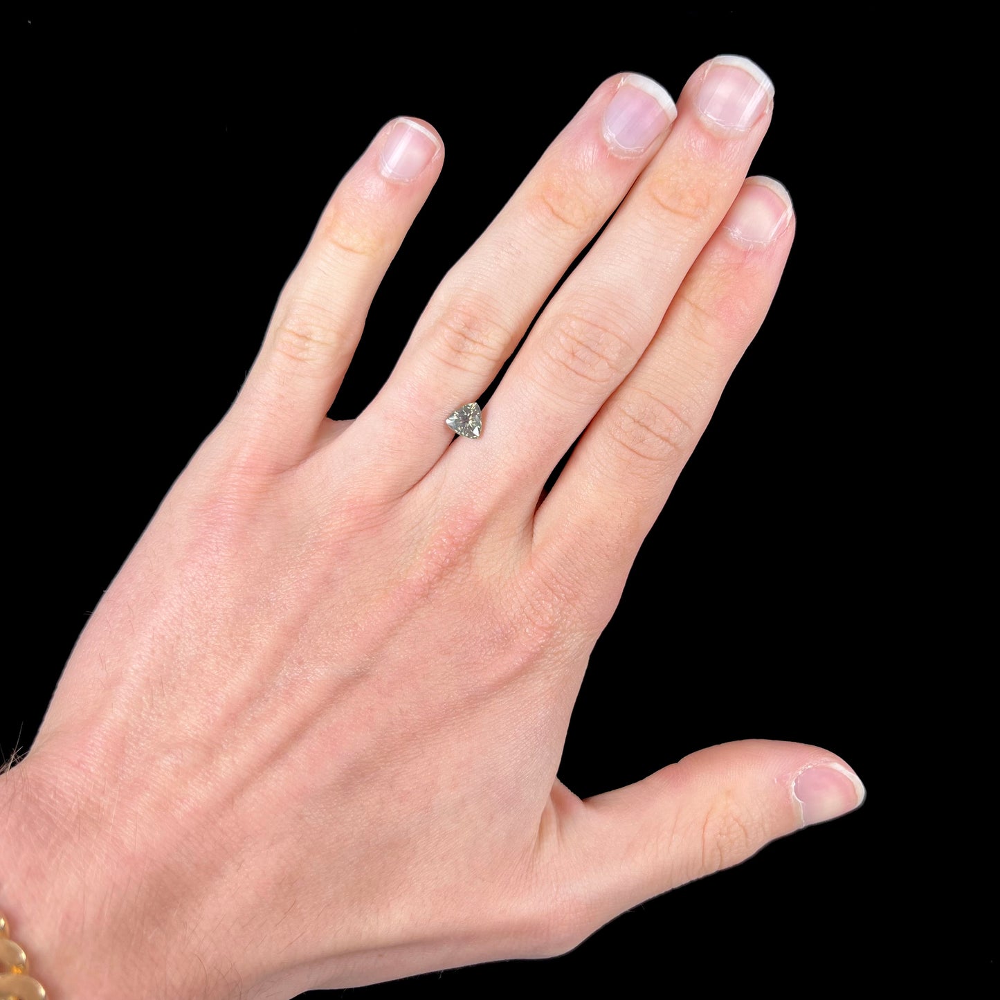 A natural, 1.10 carat, trillion cut alexandrite gemstone. The stone changes colors from dark olive green to faint purplish green.