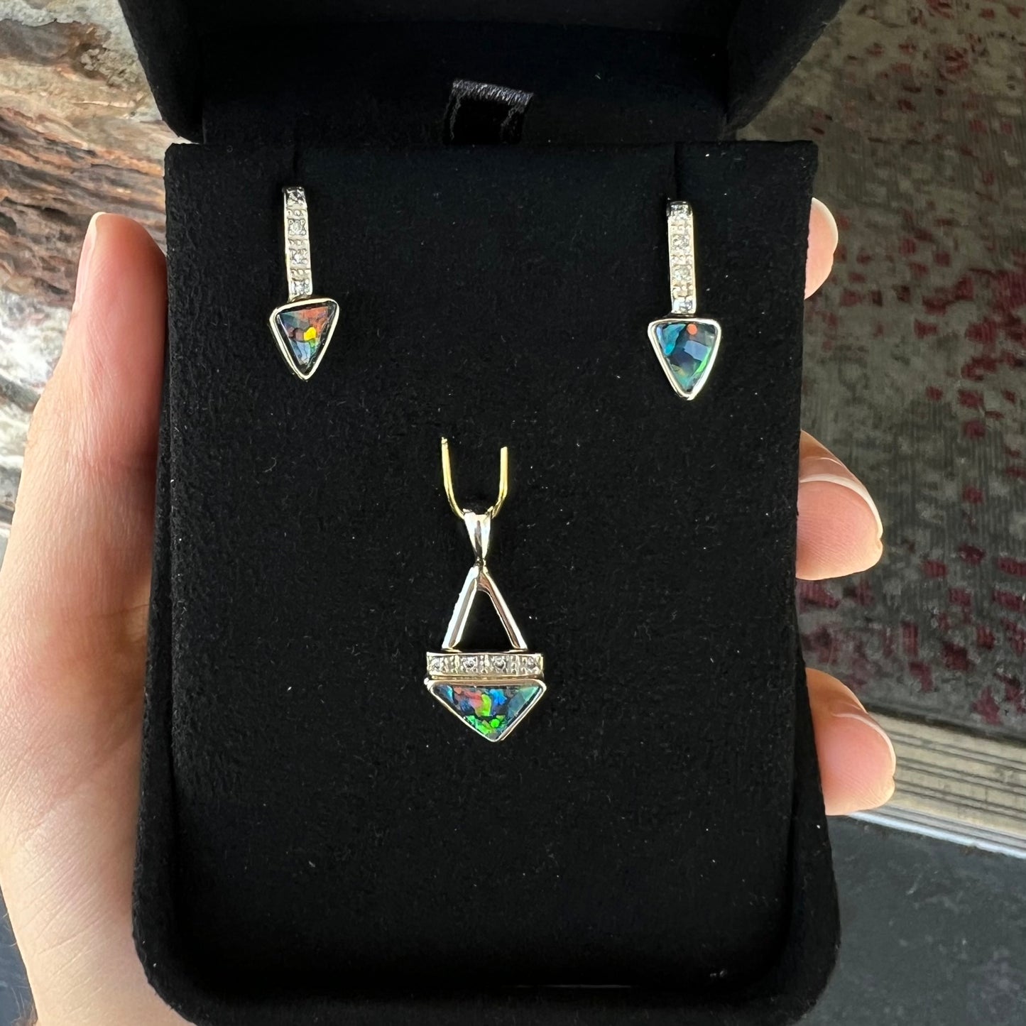 A white gold pendant and earrings set mounted with triangle cut natural black opals and diamonds.